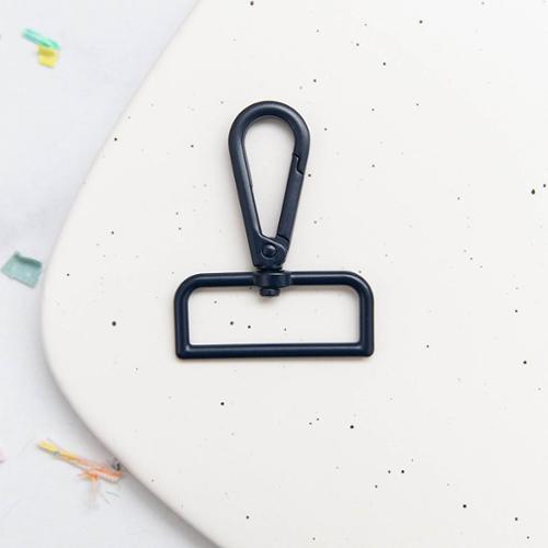Navy swivel snap hook on a white speckled surface