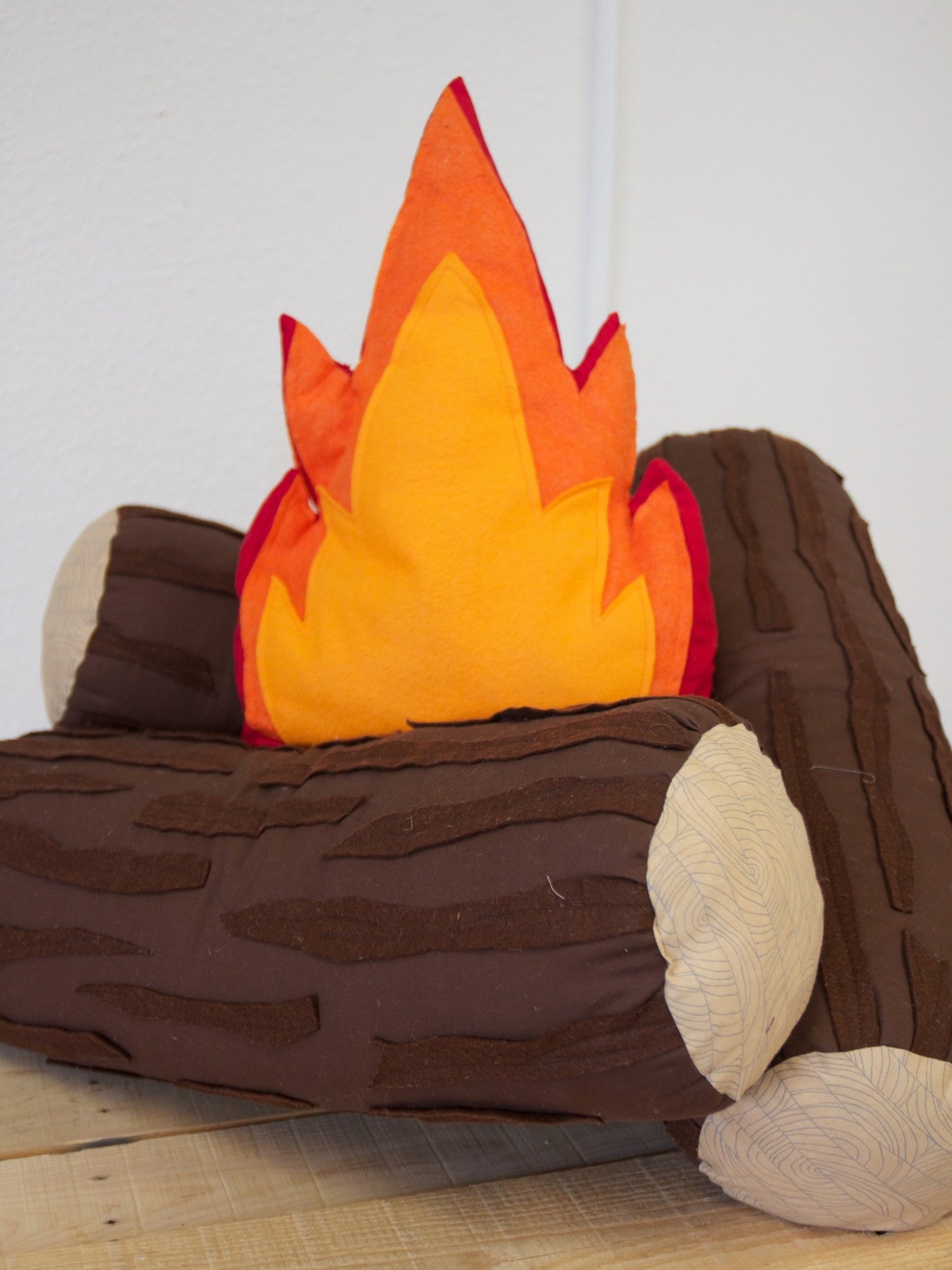 Fabric campfire pillow set with flame pillow and stacked log pillows.