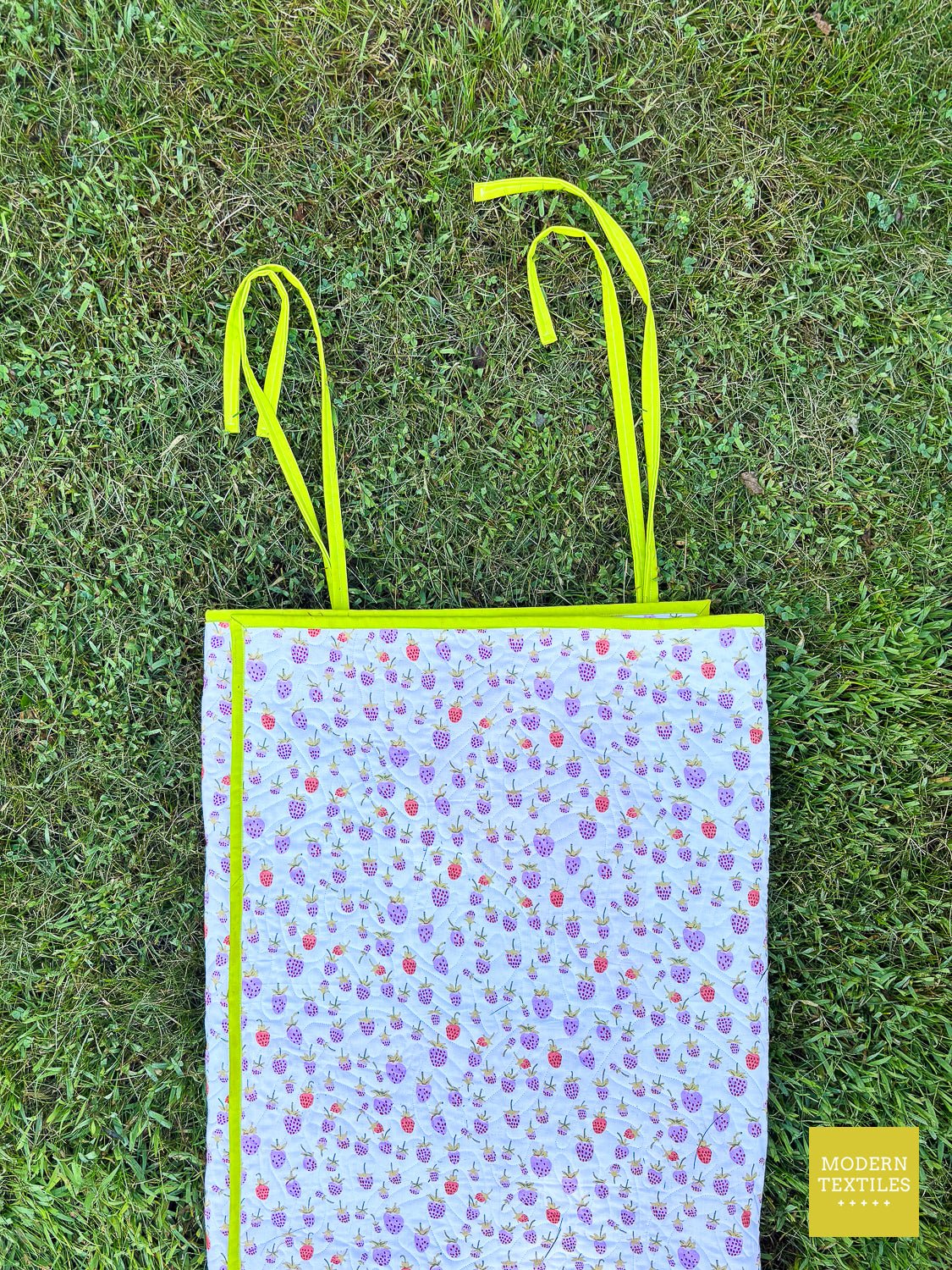 Picnic quilt backing shown, with the green quilt ties attached and ready to be rolled and tied up.