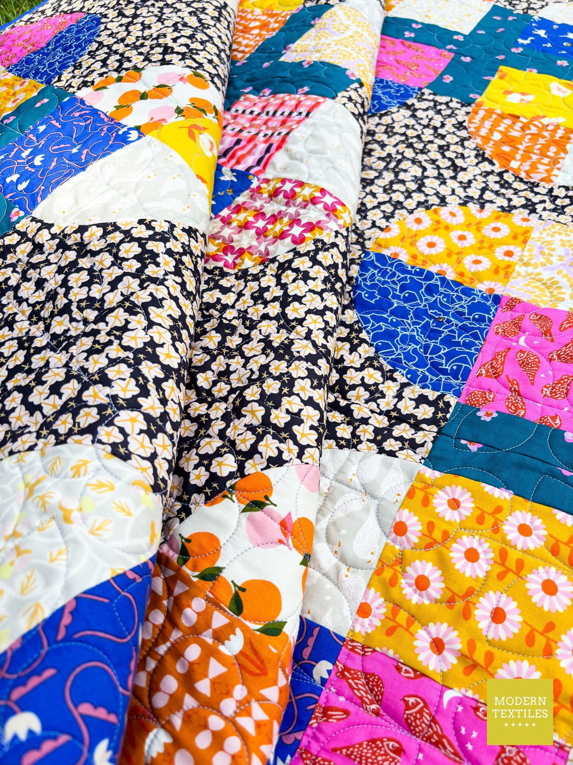 Edge detail of quilt showing curved blocks transitioning into patterned background fabric.