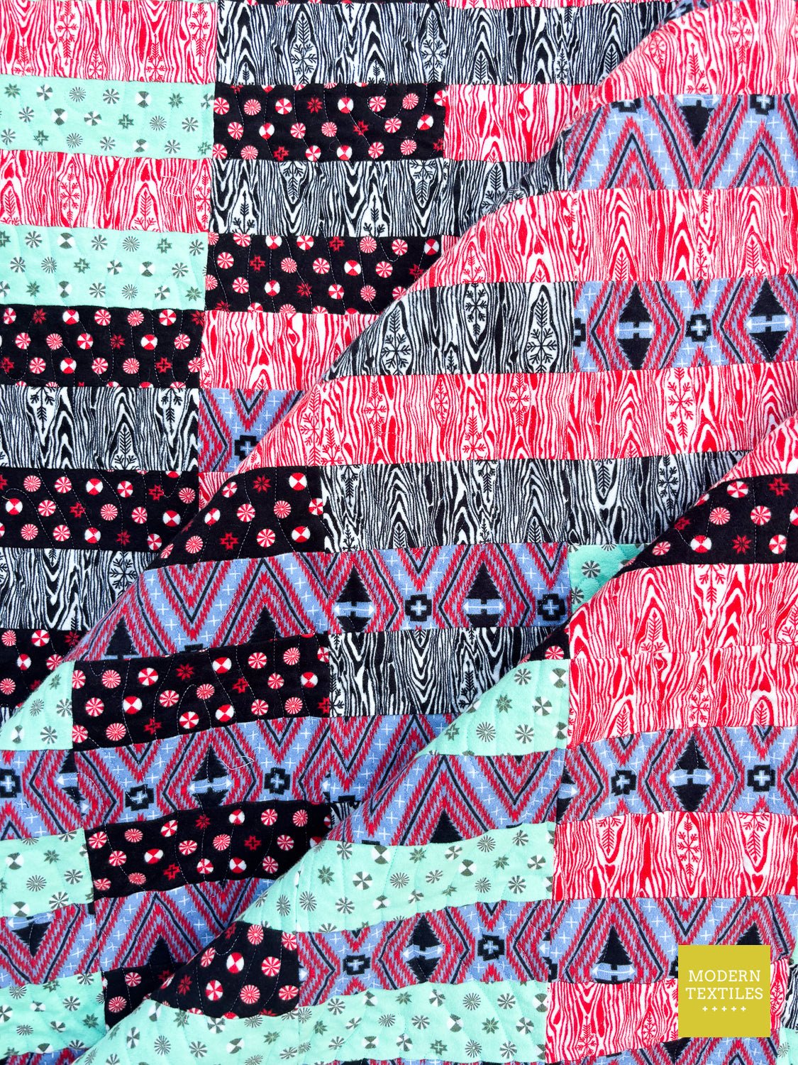 Folded detail of modern striped quilt showing contrast fabrics.