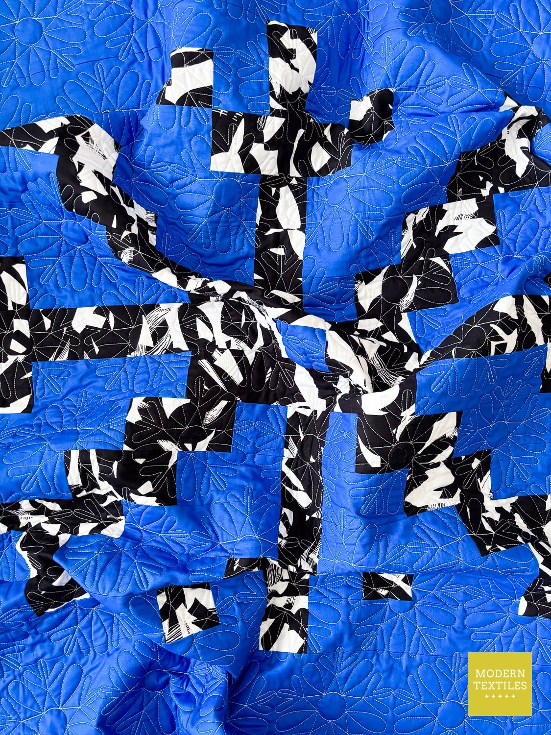 Crinkled Blue and black quilt with snowflake design, showcasing dimension of quilt.