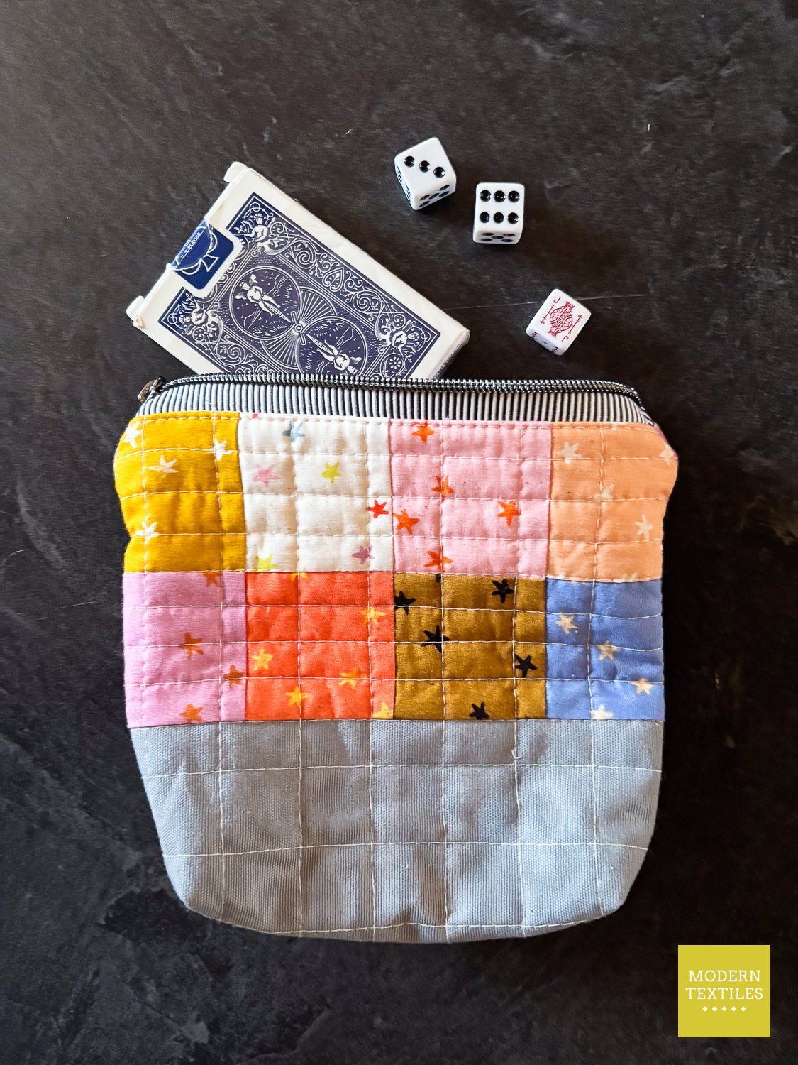 Single quilted zipper pouch with patchwork exterior and zipper closure.