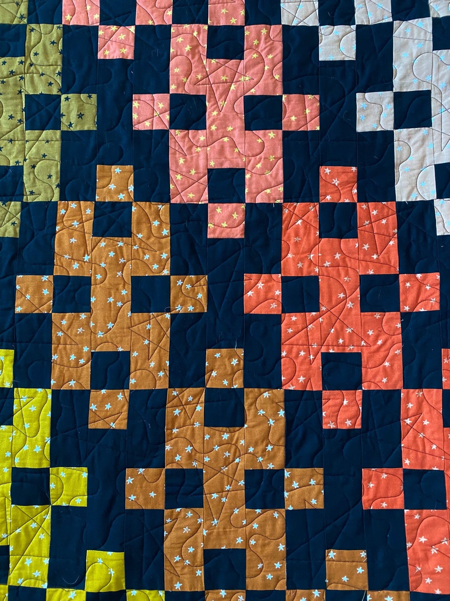 Diamond Plate quilt detail showing bold geometric blocks in gold, coral, navy, and black.
