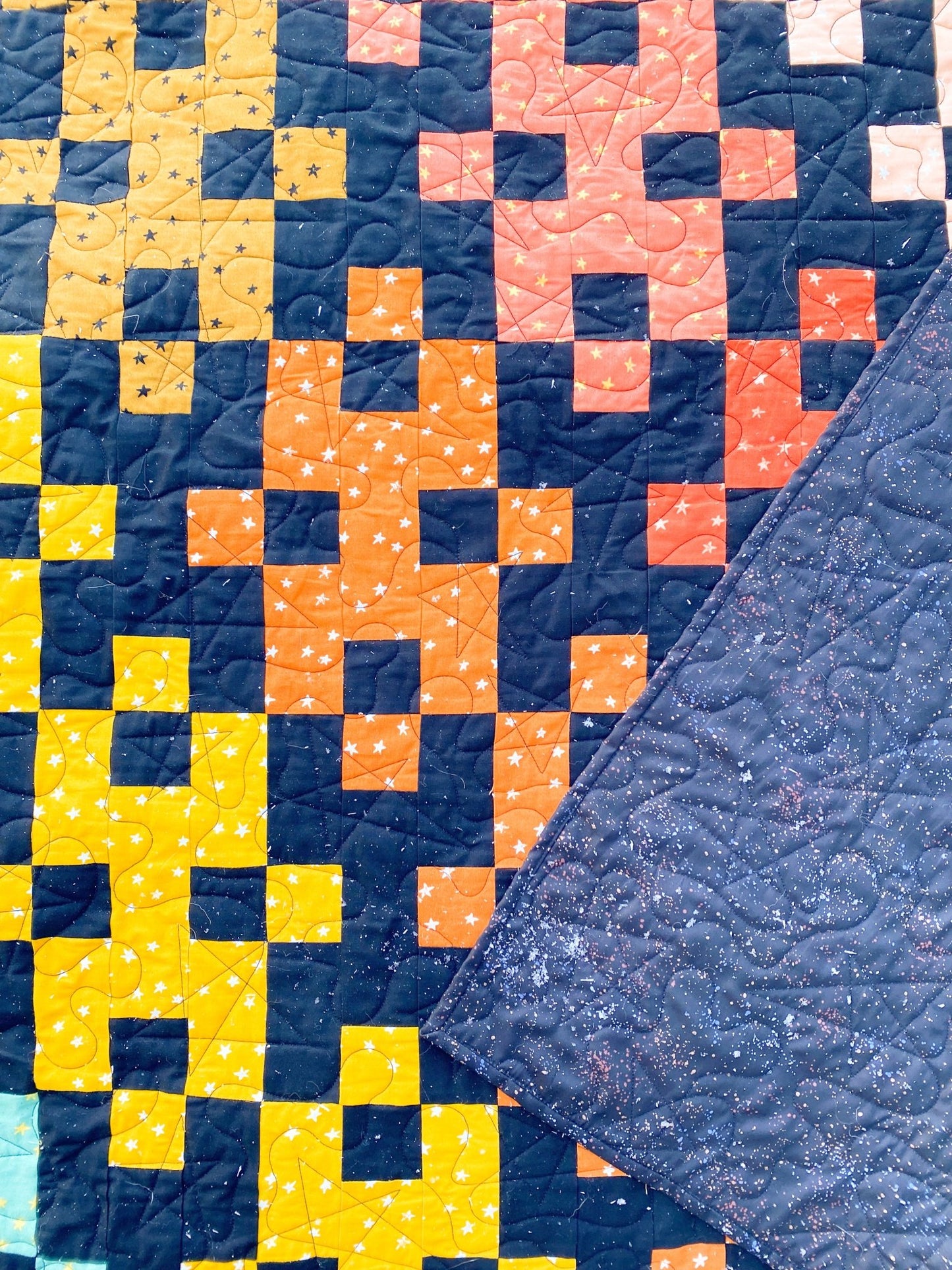 Diamond Plate quilt detail showing bold geometric blocks in gold, coral, navy, and black.