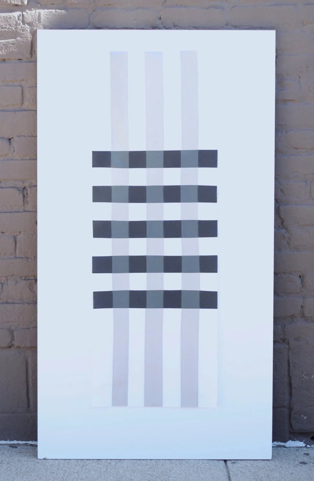 Table runner patchwork plaid quilt with minimalist black and gray plaid stripes displayed against brick wall.