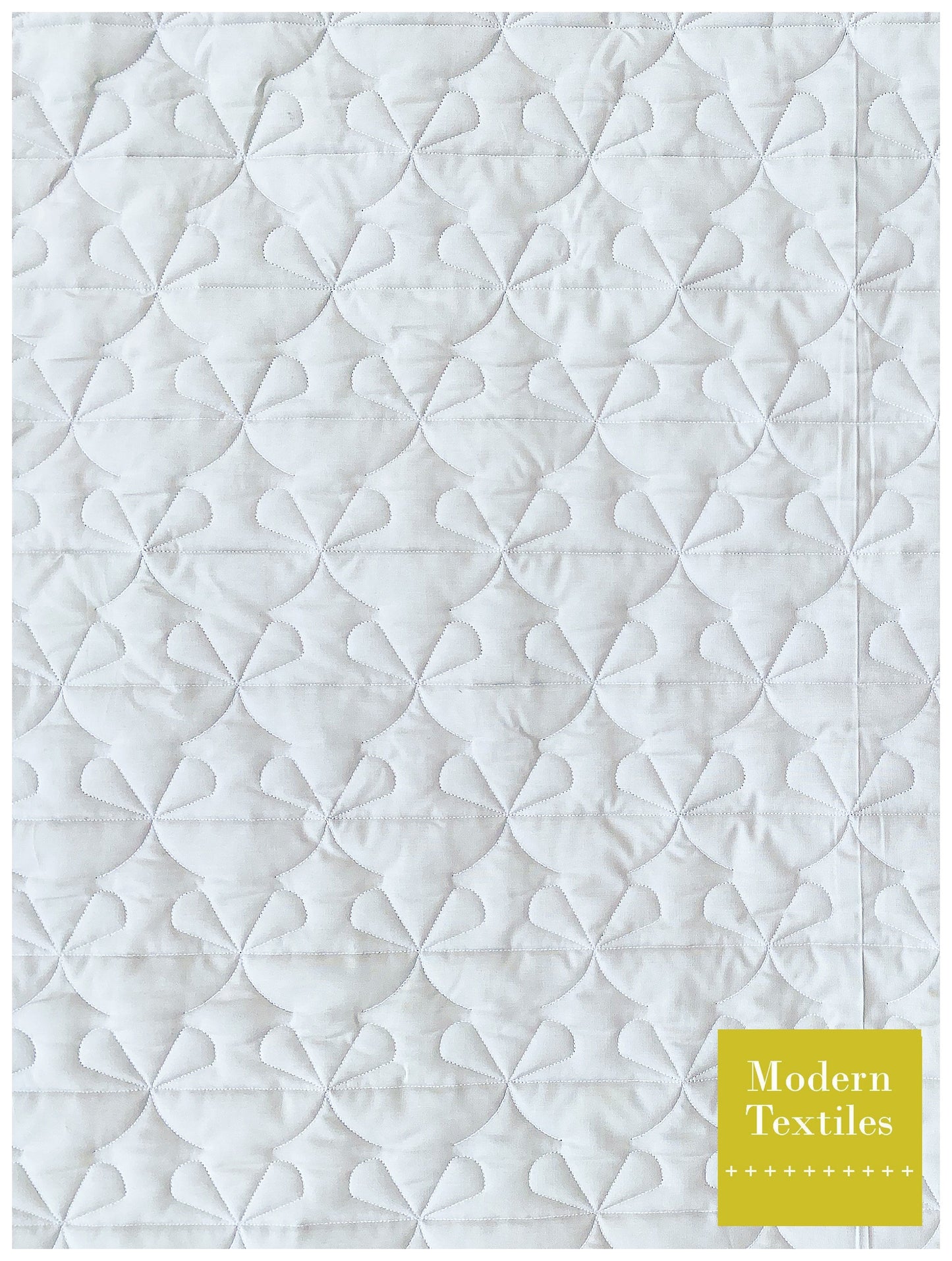 Staggered 50% offset bow shaped quilting design stitched out on wholecloth white quilt.