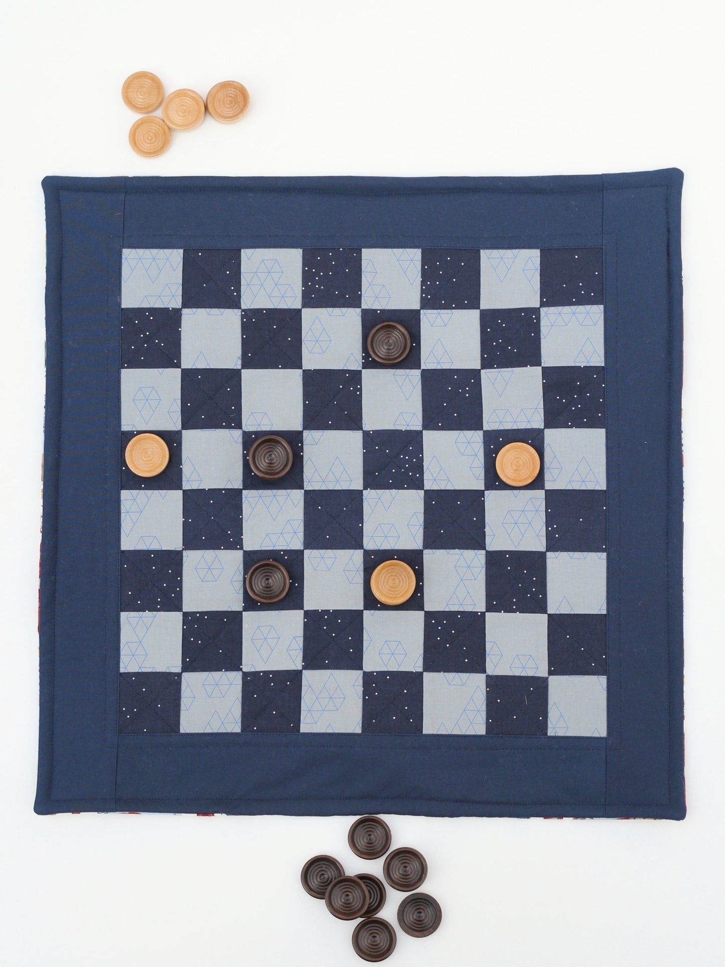 Fabric checkerboard game mat with wooden game pieces arranged on board.