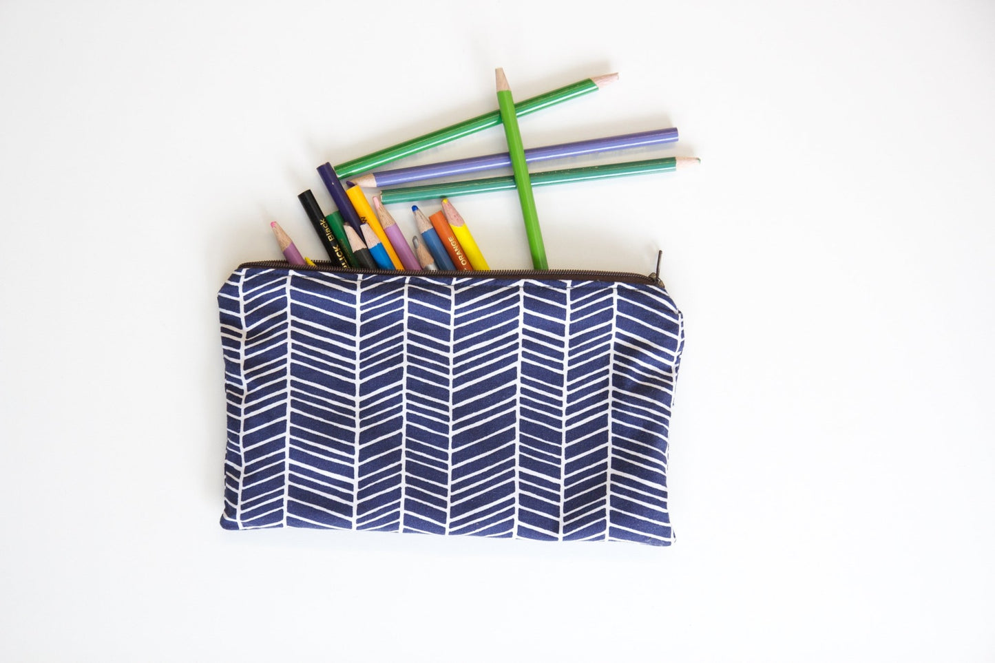 Finished zipper pouch holding colored pencils in blue geometric fabric.