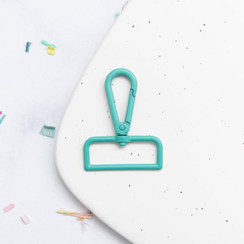 Turquoise swivel snap hook clip on a white background with colorful items.