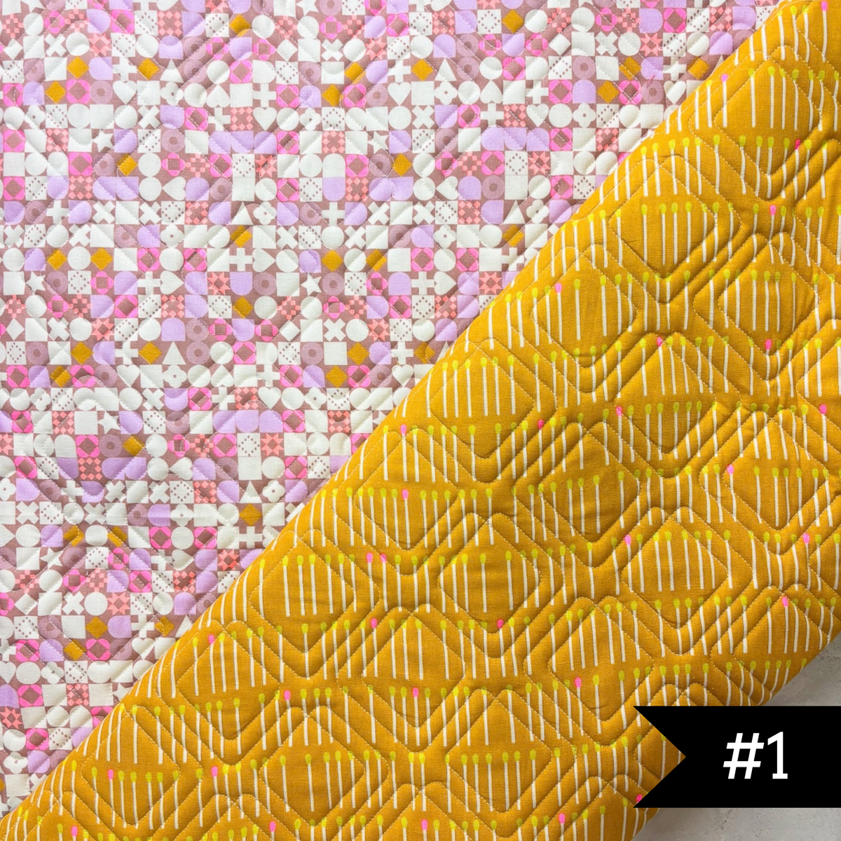 A quilted fabric panel shown diagonally, featuring a bright yellow lining fabric with white stitched diagonal plaid quilt panto and a pink, white, and yellow patchwork printed exterior. #1 in white on a black tag on lower right hand corner.