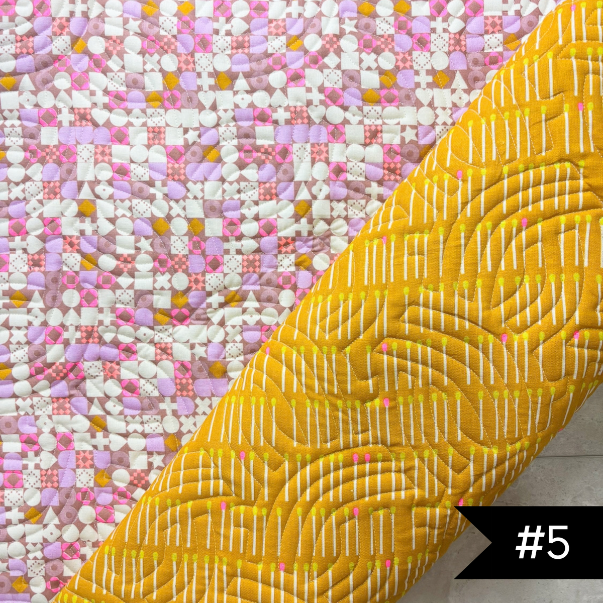 A quilted fabric panel shown diagonally, featuring a bright yellow lining fabric with white stitched Echoed Curves quilt patnto and a pink, white, and yellow patchwork printed exterior. #5 in white on a black tag on lower right hand corner.