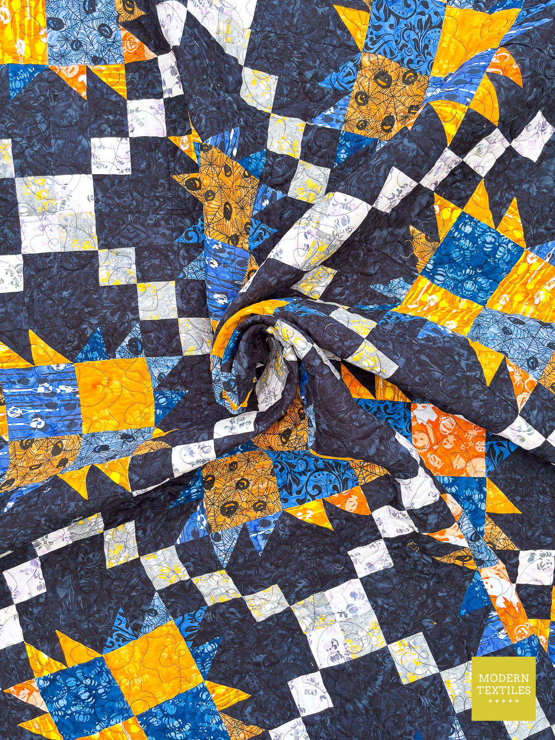 Bear Paw Irish Chain quilt with blue, orange, and white pattern on a black background twisted at the center of the quilt.