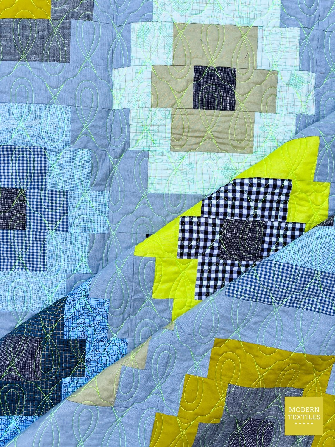 Modern Quilty Beads quilt with geometric pattern in blue, green, and yellow, stitched with neon thread.