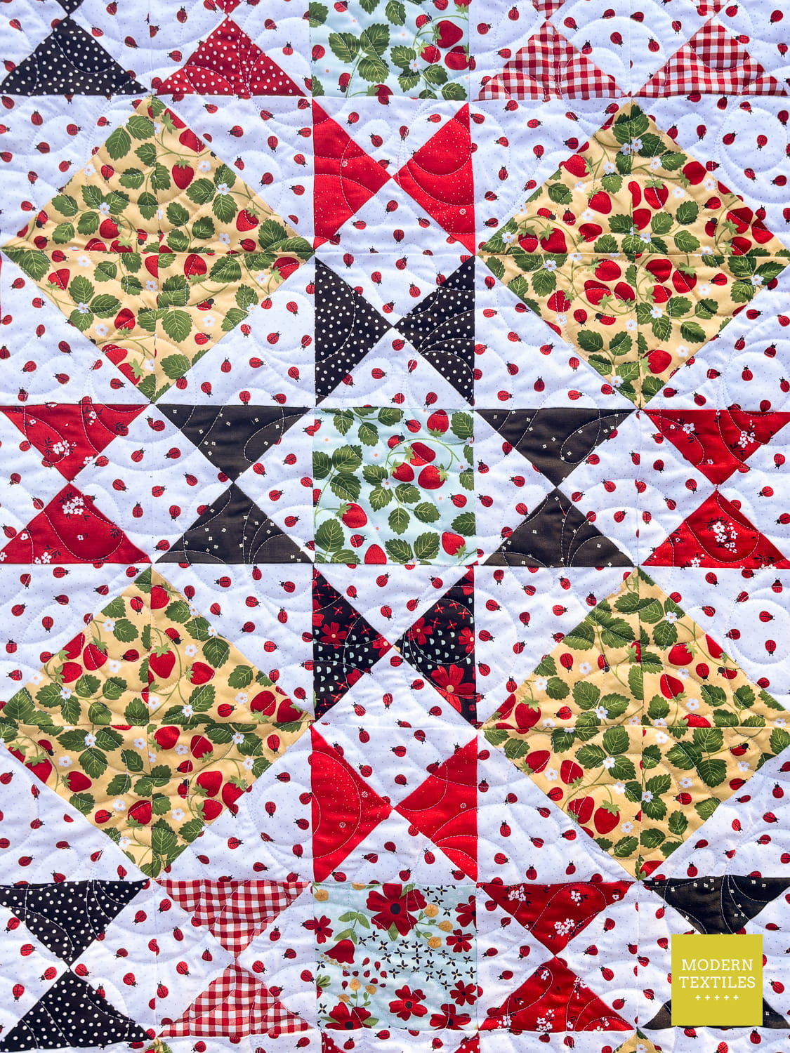 A close-up of the Ohio Star Block with red, black, green, and white patterned fabric, including strawberry prints, gingham, polka dots, and floral motifs. 'Modern Textiles Design' logo is visible in the bottom right corner.