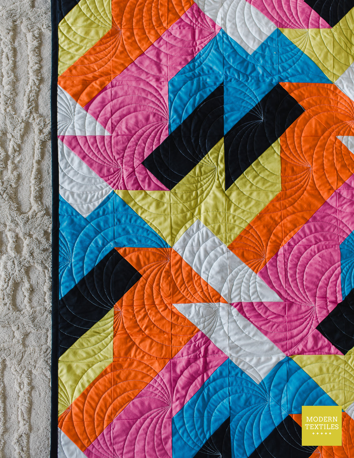 Detailed quilting close-up of the Sheared modern quilt pattern showing curved quilting texture over bold geometric patchwork blocks.