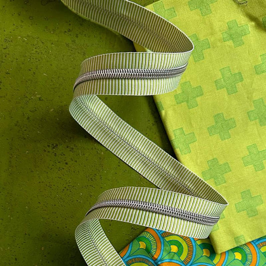 Green and white striped zipper tape with on a green background with green fabric.