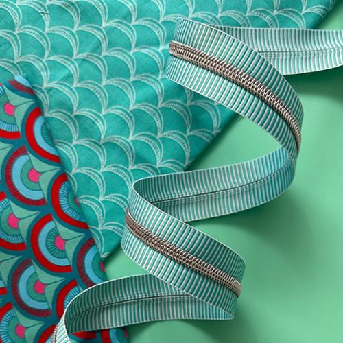 Teal and white striped zipper tape with on a teal background with teal fabric.